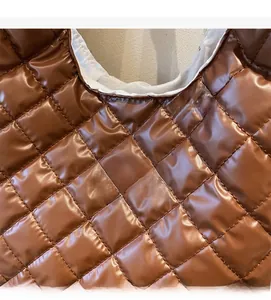 Close-up of quilted dark brown nylon tote bag with white Fashion Instinct textile label