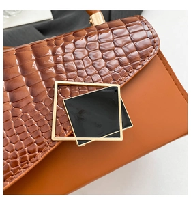 Detail of dark brown faux crocodile leather shoulder bag with gold geometric metal clasp