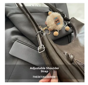 Detail view of adjustable leather shoulder strap with silver buckle on a brown tote bag