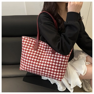 Detail of red and white houndstooth tote bag with reinforced leather handles on model