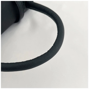 Close-up of durable black Saffiano leather handle and fine stitching on a handbag