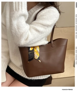 Brown leather tote bag with silk scarf detail worn by a model in a white sweater