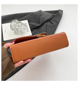 Detailed side view of a caramel leather square bag with a golden metal twist lock