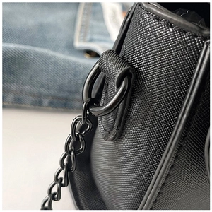 Close-up of black Saffiano leather texture and metallic hardware on shoulder bag