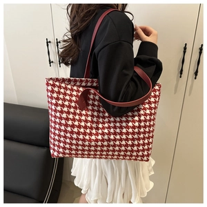 Detail of red houndstooth tote bag with leather strap shown on shoulder for daily use