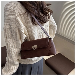 Brown retro baguette shoulder bag with metal buckle shown on a model in a warm setting