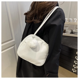 Gros plan d'un sac à bandoulière blanc minimaliste avec un pompon en peluche doux