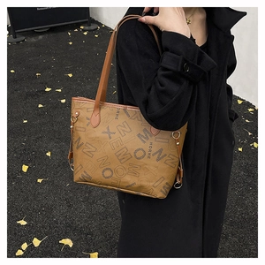 Dettaglio di una grande borsa tote in pelle PU marrone con stampe di lettere e cappotto
