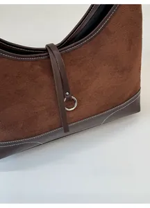 Close-up of brown suede and dark leather stitching with a silver metal ring buckle