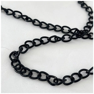 Detailed close-up of glossy black metal chain links on a white fabric texture background