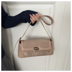 Detail of beige baguette bag showing suede and leather textures with a golden clasp