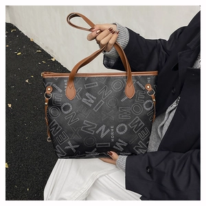 Dettaglio della borsa tote vintage nera con stampa di lettere bianche e manici marroni