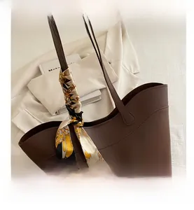 Close-up of vintage brown tote bag with leather texture and decorative silk scarf handle