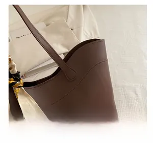 Detail of brown leather tote bag with elegant floral scarf and premium stitching