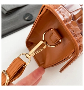 Detail of crocodile pattern leather bag with golden metallic hardware D-ring and spring hook