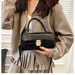Détail d'un sac à bandoulière en cuir noir avec boucle dorée et pendentif décoratif fashion