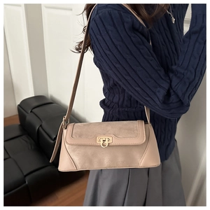 Detail of beige leather and suede baguette bag with gold metal buckle on a shoulder