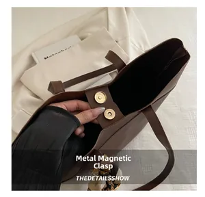 Close-up of metal magnetic buckle on brown faux leather tote with floral silk scarf