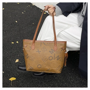 Dettaglio della borsa tote marrone vintage con stampe di lettere e nappine decorative