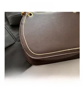 Close-up of brown leather crescent bag with golden stitching and metallic eyelet details