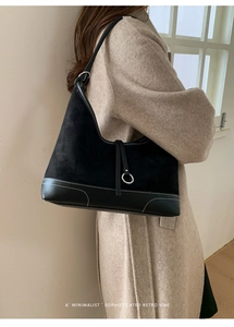 Detail of black suede and leather patchwork tote bag with white contrast stitching