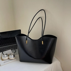 Minimalistische schwarze glänzende Tragetasche aus Kunstleder mit eleganten Goldbeschlägen