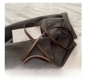 Close-up of adjustable brown leather shoulder strap with gold-tone hardware and buckles