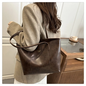 Detail of a deep brown faux leather tote bag with elegant gold foil fashion lettering