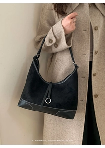 Detail of suede and smooth black leather tote bag with white stitching and silver ring buckle