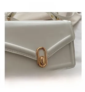 Nahaufnahme der weißen Ledertasche mit goldenem Oval-Drehverschluss und feinen Nähten