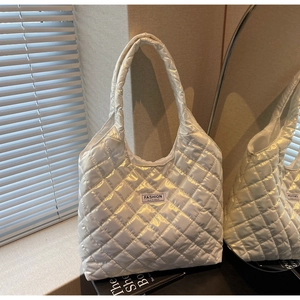Detail of white quilted tote bag with glossy finish and Fashion Instinct textile label