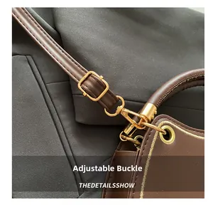 Detailed close-up of brown leather bag with adjustable golden buckle and stitching