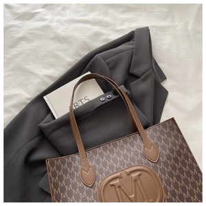 Vue détaillée du sac cabas marron avec motif monogramme M et logo rond en relief