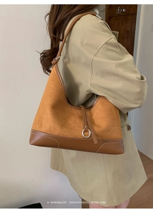 Close-up of brown suede hobo bag with leather trim and silver ring buckle detail