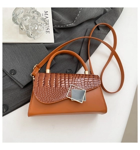 Detail of caramel brown handbag with crocodile texture flap and gold metal buckle