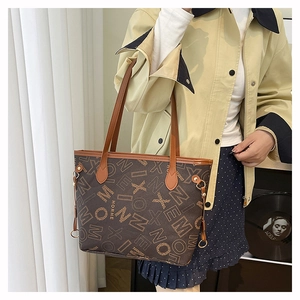 Dettaglio di una borsa tote marrone con stampa a lettere, logo HORHE e manici in pelle