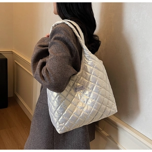 Close-up of silver quilted tote bag with Fashion Instinct label and glossy texture