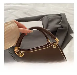 Detail of dark brown saddle bag featuring thick round handle and golden metal hardware