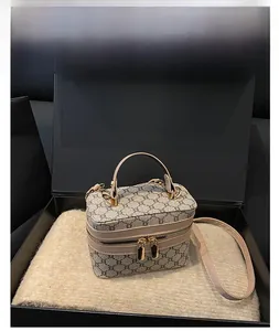 Detailed side view of khaki monogram canvas box bag with gold-tone hardware in a gift box