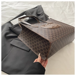 Sac fourre-tout marron avec imprimé M intégral et logo en relief sur lit blanc