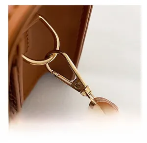 Dettaglio di borsa in pelle marrone con gancio in metallo dorato e tracolla