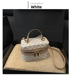Detailed view of white vintage monogram box bag with golden hardware on a plush gift box