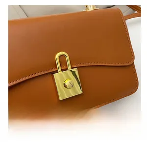 Dettaglio del lucchetto in metallo dorato su borsa a tracolla minimalista in pelle marrone
