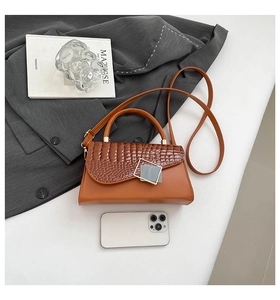 Macro shot of brown crossbody bag with mock croc texture and silver square buckle detail