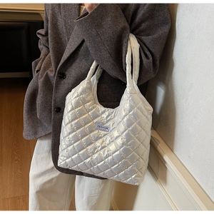 Quilted shiny shoulder bag with Fashion Instinct label worn by model in brown suit