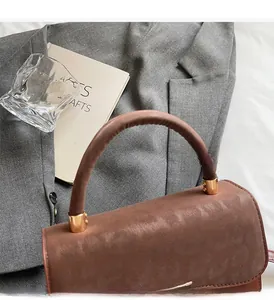 Close-up of caramel brown handbag featuring smooth leather handles and gold hardware details