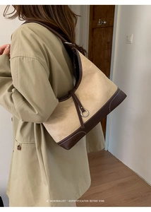 Detail of retro color-block suede dumpling bag worn over the shoulder with khaki trench coat