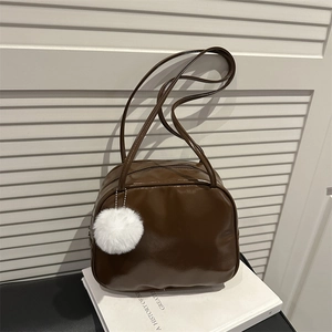Sac polochon en cuir verni marron foncé brillant avec charm en peluche blanc et bretelles