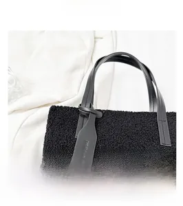 Detail of plush black faux shearling texture and premium leather strap on shoulder bag