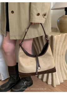 Detail of suede and leather patchwork dumpling bag with contrast stitching and adjustable strap